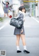 A woman in a school uniform is walking down the street.