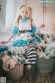 A woman sitting on top of a bed next to a basket of flowers.