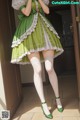 A woman in a green and white dress and stockings.