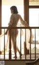 A woman standing on a balcony looking out a window.