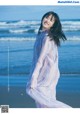 A woman standing on a beach next to the ocean.