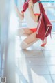 A woman in a red and white uniform crouching on the floor.