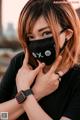 A woman wearing a black face mask with chinese characters on it.