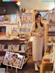 A woman standing in front of a book shelf filled with books.