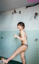 A woman in a bikini standing in a shower.