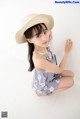 A young girl wearing a straw hat sitting on the floor.